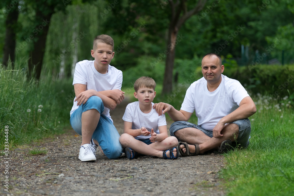 A father with his sons sits on the ground. Family portrait. A father with his sons sits on the ground. Family portrait.