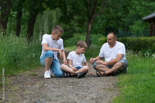 A father with his sons sits on the ground. Family portrait.