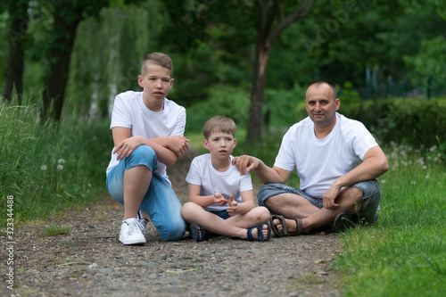 A father with his sons sits on the ground. Family portrait. © Sergey Kohl