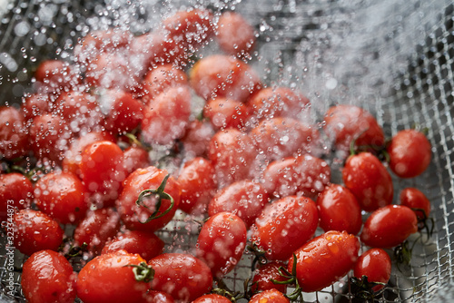 Cleaning the vivid red ripe tomatoes in the metal wire basket