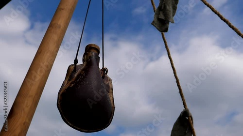 Old leather bottle or water skin swinging against sky at viking reenactment camp.