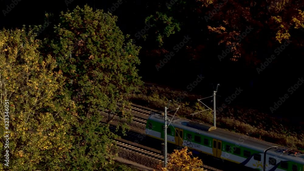 The commuter train is passing through the trees in the evening. The commuter train is passing through the trees in the evening.