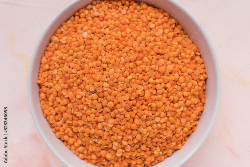 Raw red lentils in ceramic bowl on pink background, concept of healthy eating vegan food. Close up, selective focus Raw red lentils in ceramic bowl on pink background, concept of healthy eating vegan food. Close up, selective focus