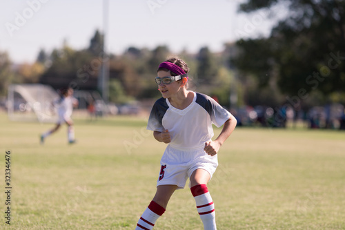 A girl with sports goggles is playing competitive soccer.