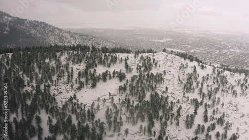Flying over snow covered mountain in a snow storm. Drone aerial view outside Boulder, Colorado. 4k view of the forest, clouds and trees above the Rocky Mountains