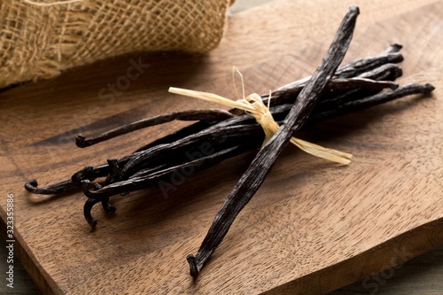 Bundle of tied, dried bourbon vanilla beans or pods on brown wooden cutting board photo