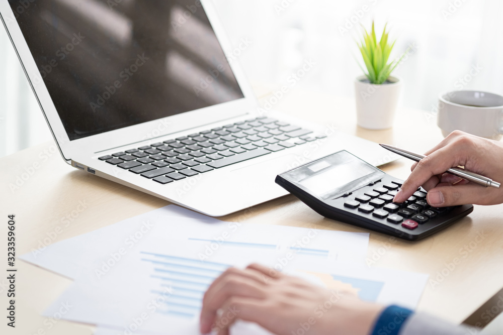Young businessman is calculating for the financial reports documents and inspecting the results. Business auditing and analyzing concept. Young businessman is calculating for the financial reports documents and inspecting the results. Business auditing and analyzing concept.