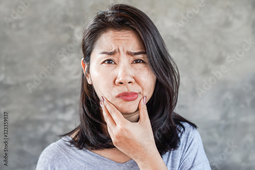 depressed Asian woman having problem with Bell's Palsy/Facial Palsy, hand holding her face  photo