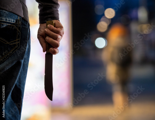 A criminal chases a person at night in a city. He is holding a knife. Concept: crime