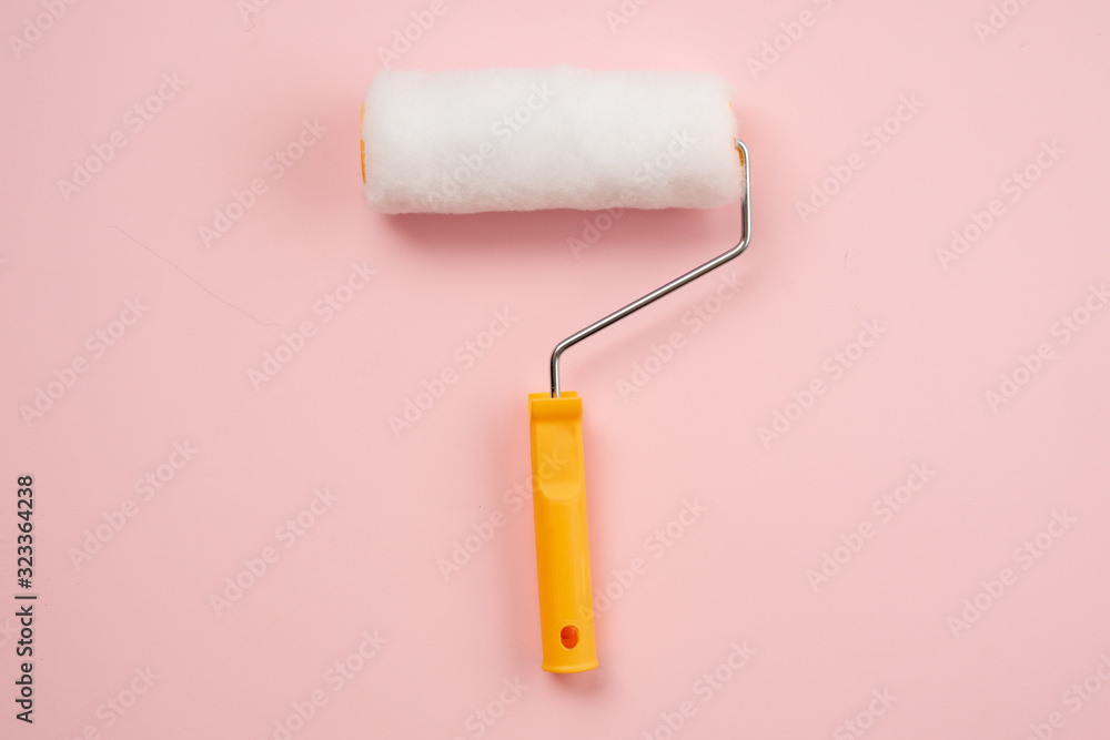 Obraz premium A yellow construction roller lies on a pink background. Tools for repair