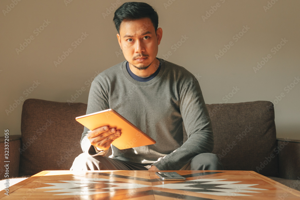 Man is using his smart tablet device in his living room apartment. Man is using his smart tablet device in his living room apartment.