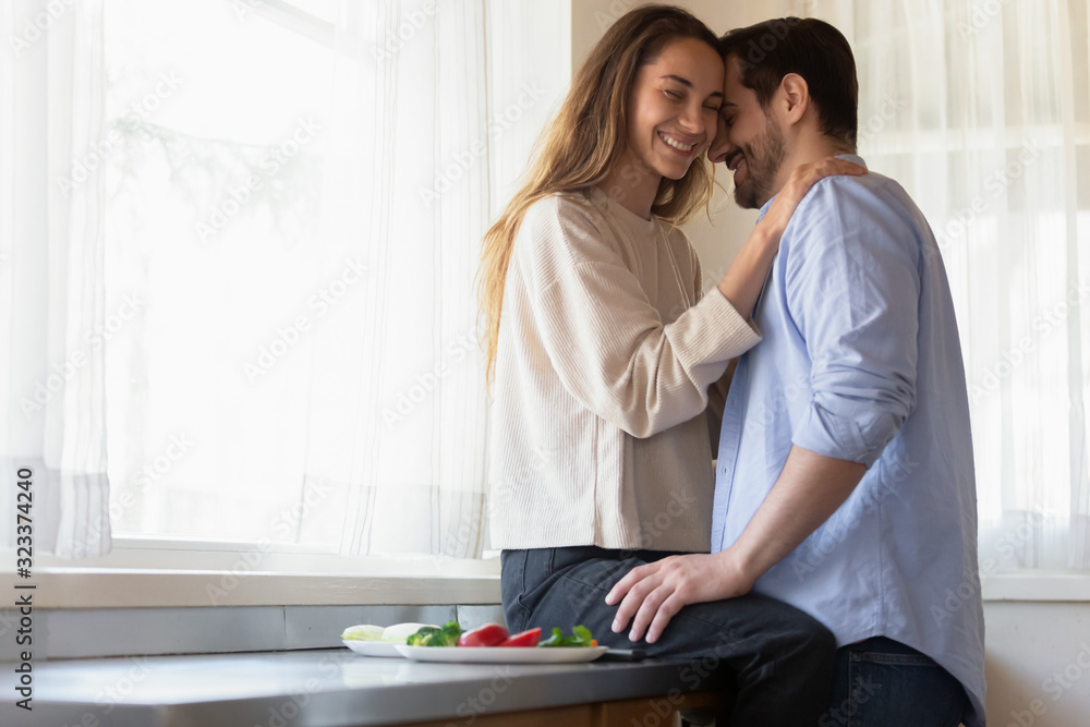 Loving happy newlyweds cuddle cooking in kitchen at home Loving happy newlyweds cuddle cooking in kitchen at home