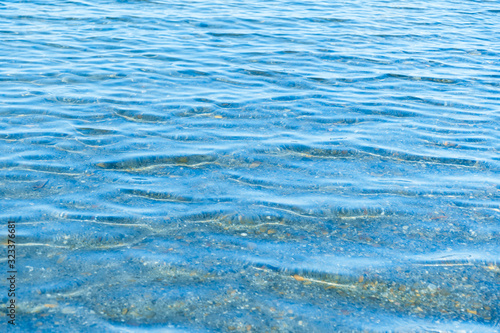 Sea blue water surface with waves near the shore. Background texture.