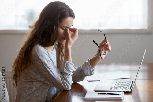 Tired young woman massage eyes suffering from headache photo