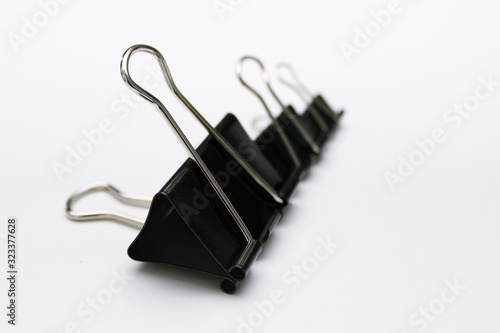 Fotografie Three black office paper clips lying in a row on a white background