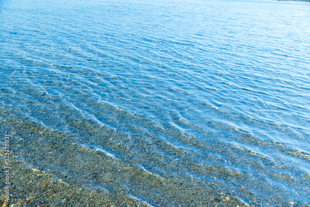 Sea blue water surface with waves near the shore. Background texture. Sea blue water surface with waves near the shore. Background texture.