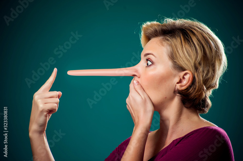 Woman touching her long nose because of lie . People,lifestyle and emotions concept