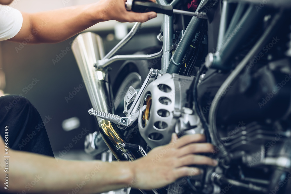 Bike repair. Young man repairing  motobike in garage.mechanic fixing motocycle engine.Serious young man repairing his motorcycle in bike repair shop.