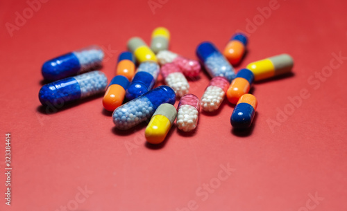 Heap of pills, tablets, capsules on red background. Drug prescription for treatment medication health care concept wth copy space.
