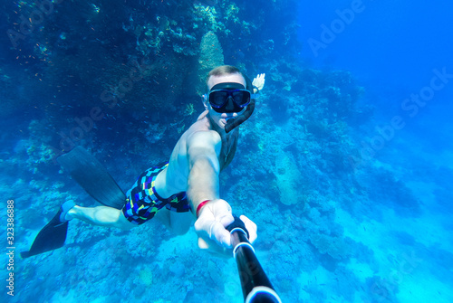 A guy with a mask and snorkel dives into the blue water of the Red Sea and photographs himself