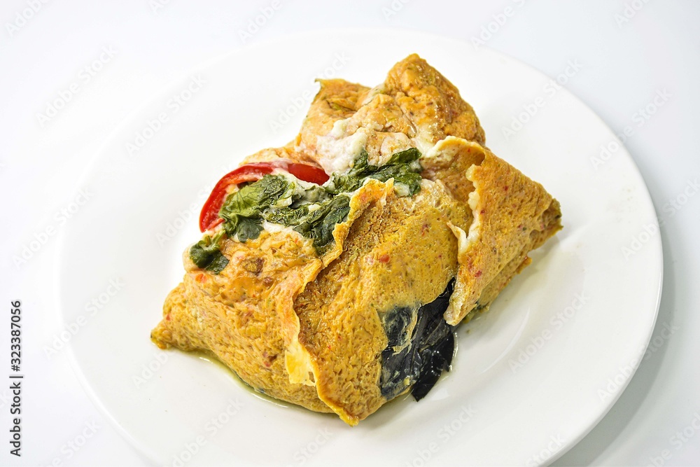 Thai Steamed Curried Fish in banana leaf placed on a white dish. Thai Steamed Curried Fish in banana leaf placed on a white dish.