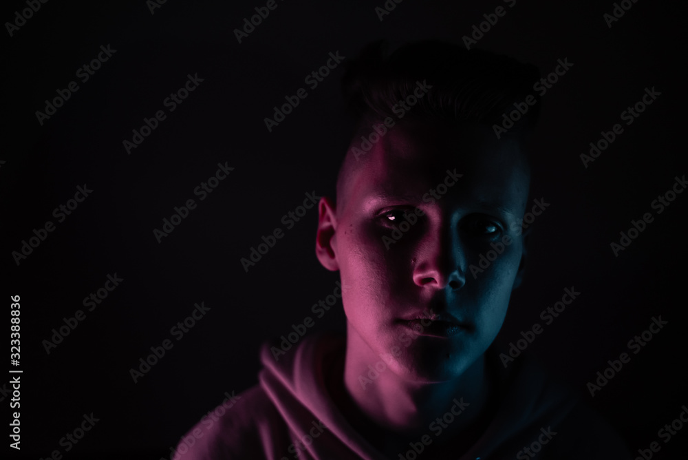 Young guy in a neon light. A teenager in a pink hoodie in trendy lighting of pink, purple and blue. Copyspace Young guy in a neon light. A teenager in a pink hoodie in trendy lighting of pink, purple and blue. Copyspace