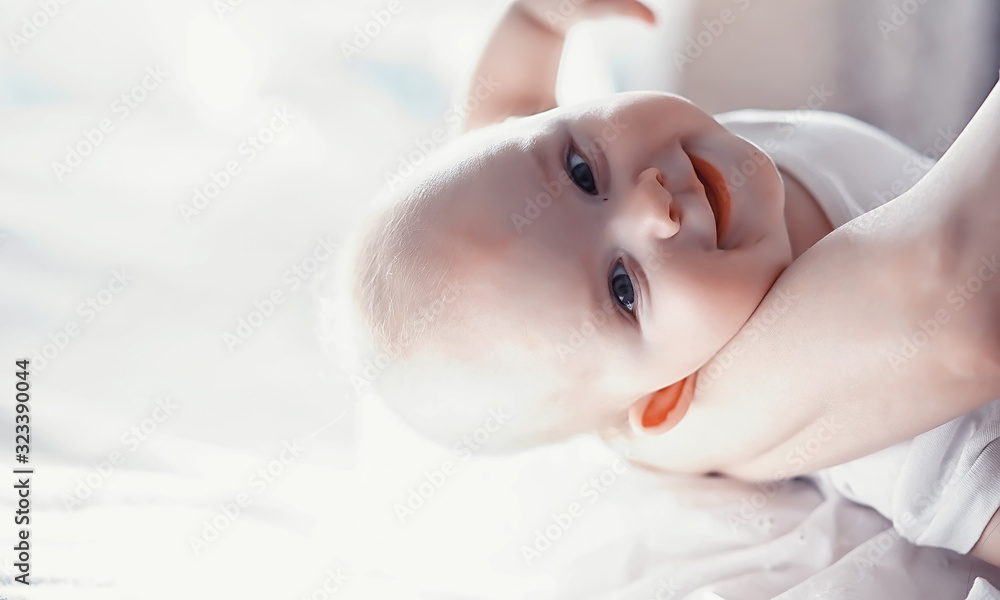 Fototapeta premium Maternity concept. A young mother feeds her little baby. First lure and breastfeeding. Family in white clothes.