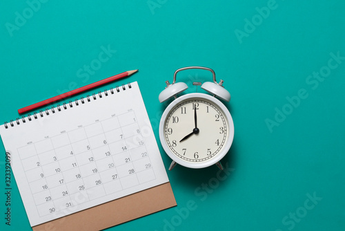 Photography close up of calendar and alarm clock on the green table, planning for business m