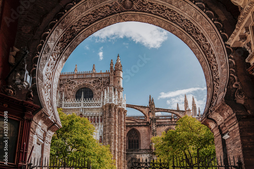 Beauty of Seville Cathedral. View to cathedral North facade and Oranges yard through the arch gate. Largest Gothic church in the world. Cathedral of Saint Mary of the See, Andalusia, Spain, Europe