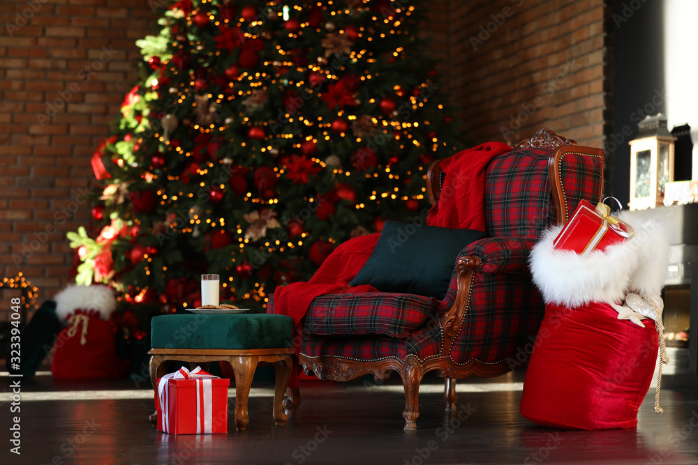 Obraz premium Santa Claus bag near armchair in room with Christmas tree