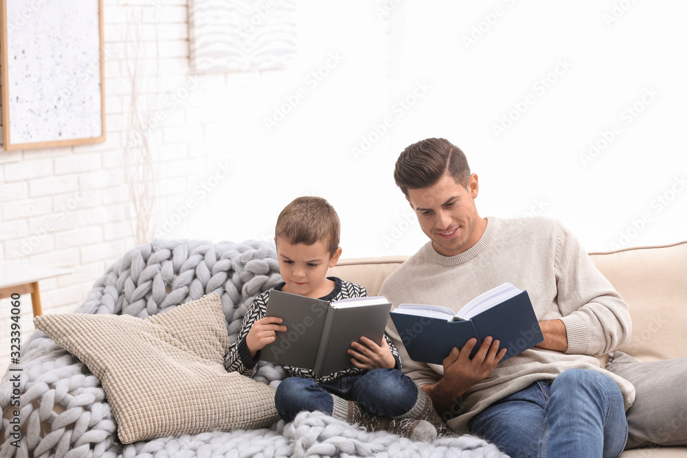 Father and his son reading books at home. Winter vacation