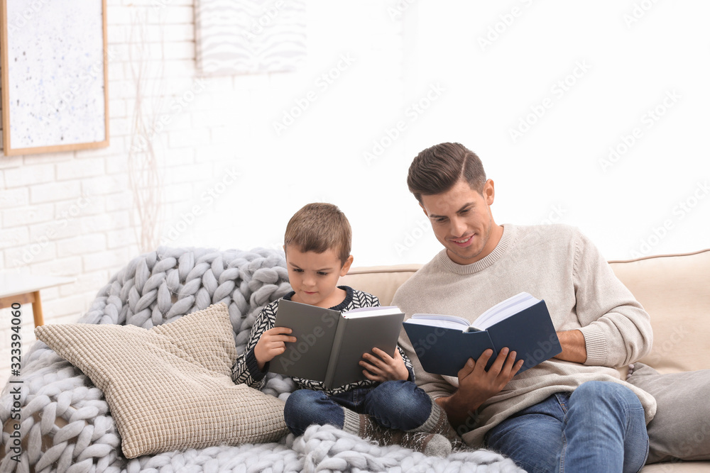 Father and his son reading books at home. Winter vacation Father and his son reading books at home. Winter vacation