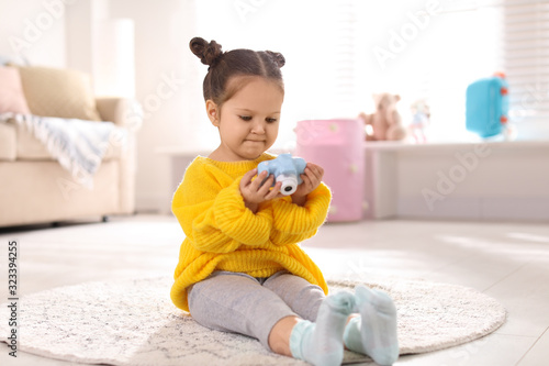 Little photographer with toy camera on floor at home