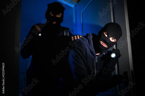 Fototapeta Naklejka Na Ścianę i Meble -  Thieves with flashlights breaking into house at night