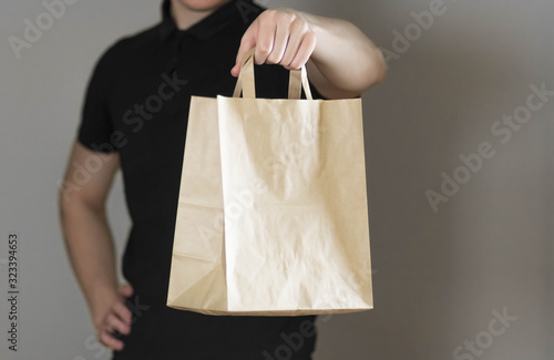 A man holds a paper bag. Close up. Isolated on a gray background