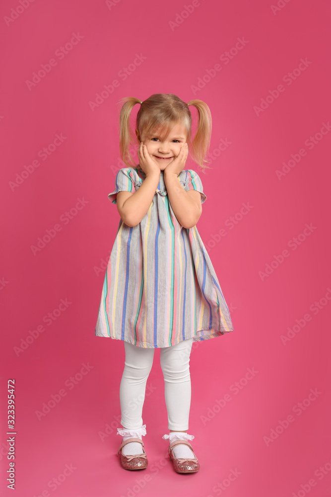 Portrait of cute little girl on pink background