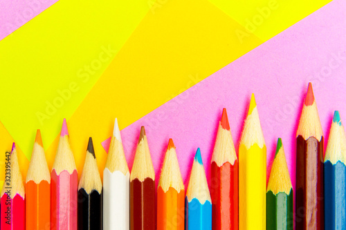 Colored pencils on the multi-colored paper background.Concept back to school. Geometric paper texture background. Template