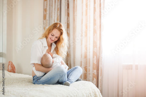 copy space tender mother breastfeeds her baby sitting on bed