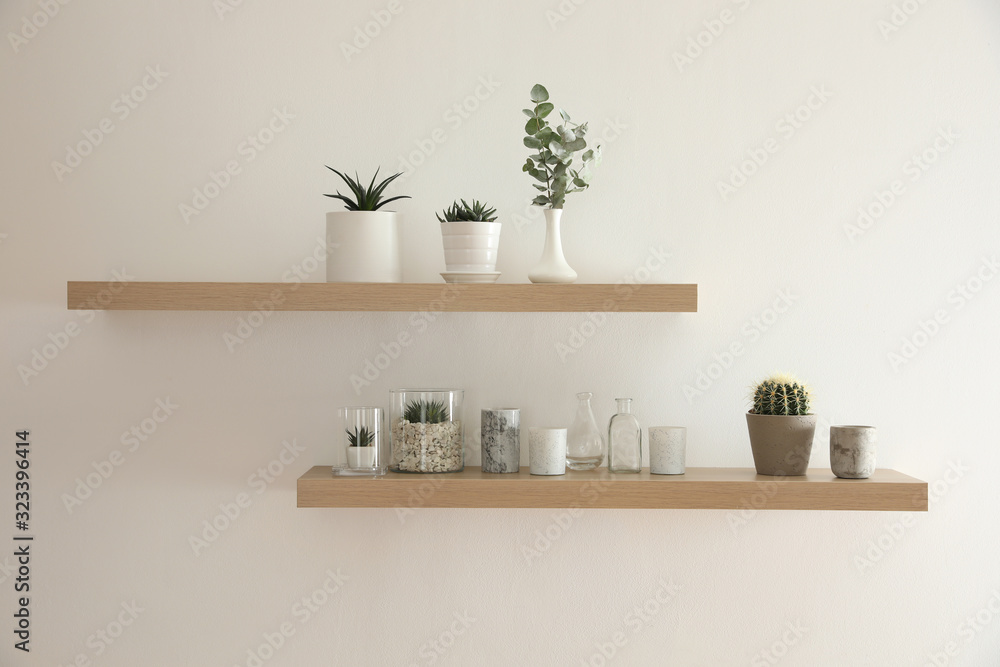 Wooden shelves with plants and decorative elements on light wall Wooden shelves with plants and decorative elements on light wall