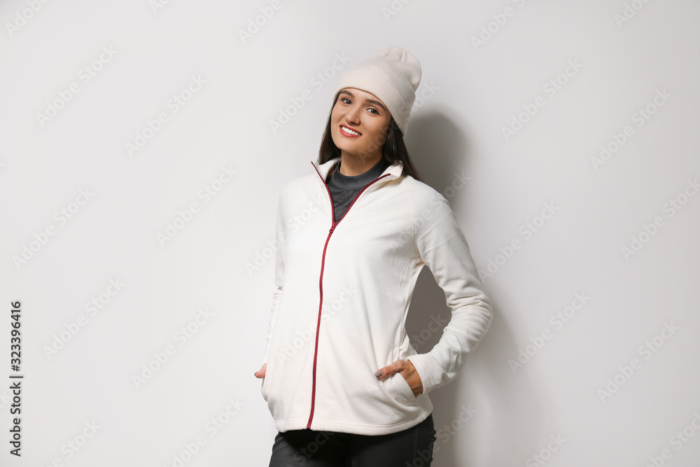 Woman wearing fleece jacket and hat on light grey background. Winter sport clothes Woman wearing fleece jacket and hat on light grey background. Winter sport clothes