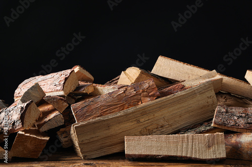Fototapeta Cut firewood on table against black background