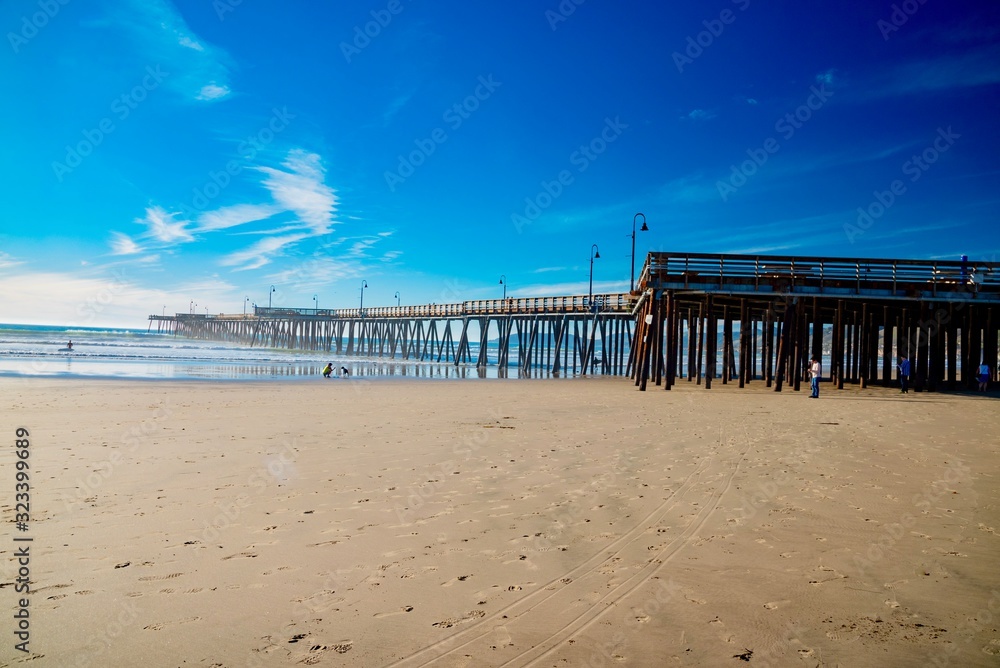 Surfers on the wooden pier of Pismo Beach in California