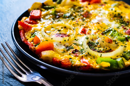 Foto Breakfast - scrambled eggs with vegetables on black stone background