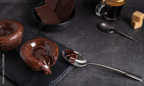 Tableau sur toile Warm chocolate lava cake on a black plate with a cup of coffee on a dark backgro