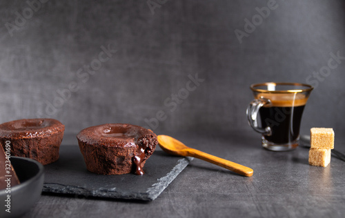 Foto Warm chocolate lava cake on a black plate with a cup of coffee on a dark backgro