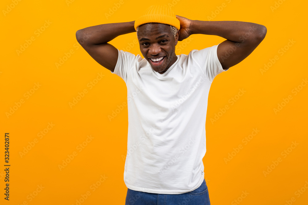 handsome charming black african man threw his arms over his shoulders on a yellow isolated studio background handsome charming black african man threw his arms over his shoulders on a yellow isolated studio background
