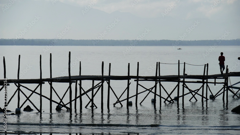 Silhouette of a wooden platform and a man standing early in the morning at a fishing village in Davao Oriental.