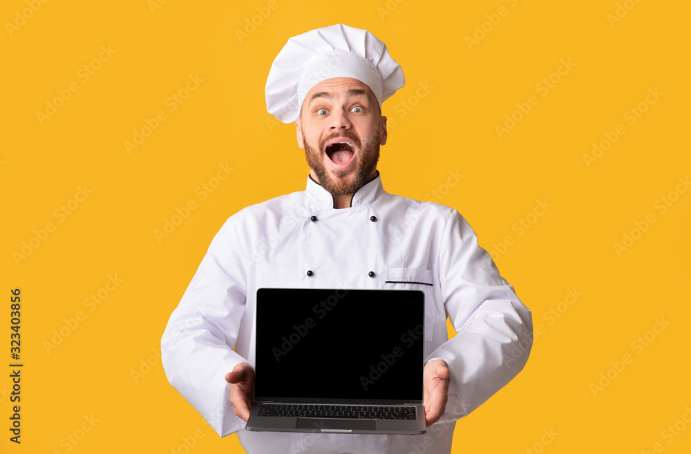 Excited Male Chef Showing Laptop Blank Screen, Yellow Background Excited Male Chef Showing Laptop Blank Screen, Yellow Background