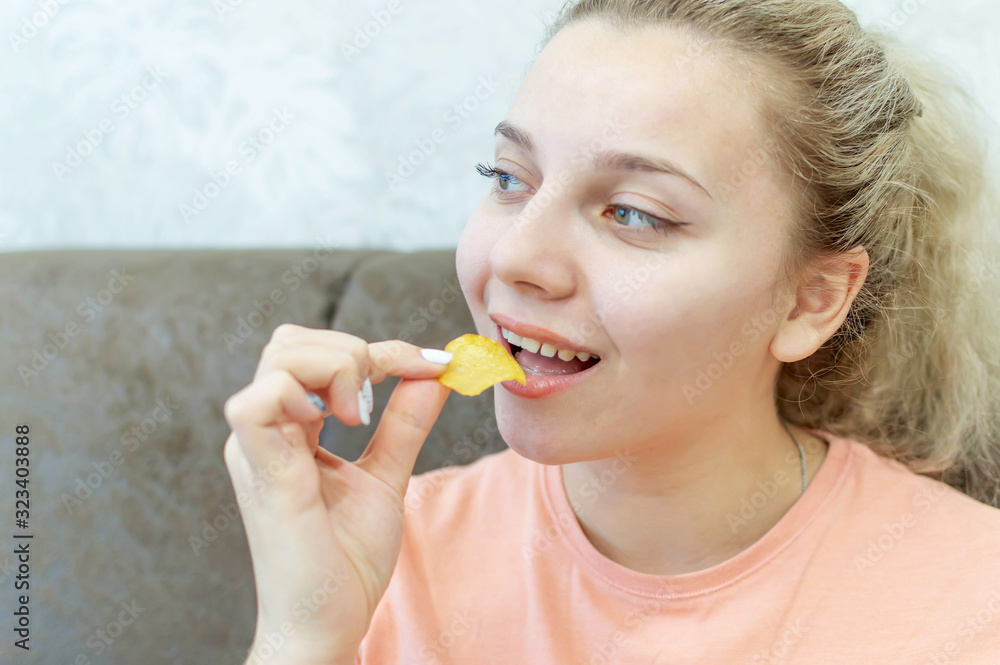 An overweight girl eats potato chips. Junk food. Selective focus, film grain. An overweight girl eats potato chips. Junk food. Selective focus, film grain.