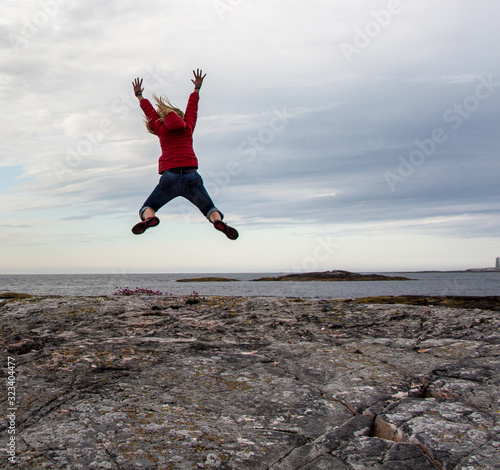 Tourist woman jumping at Norwegian sea side. Concept of freedom , happiness, travel lifestyle